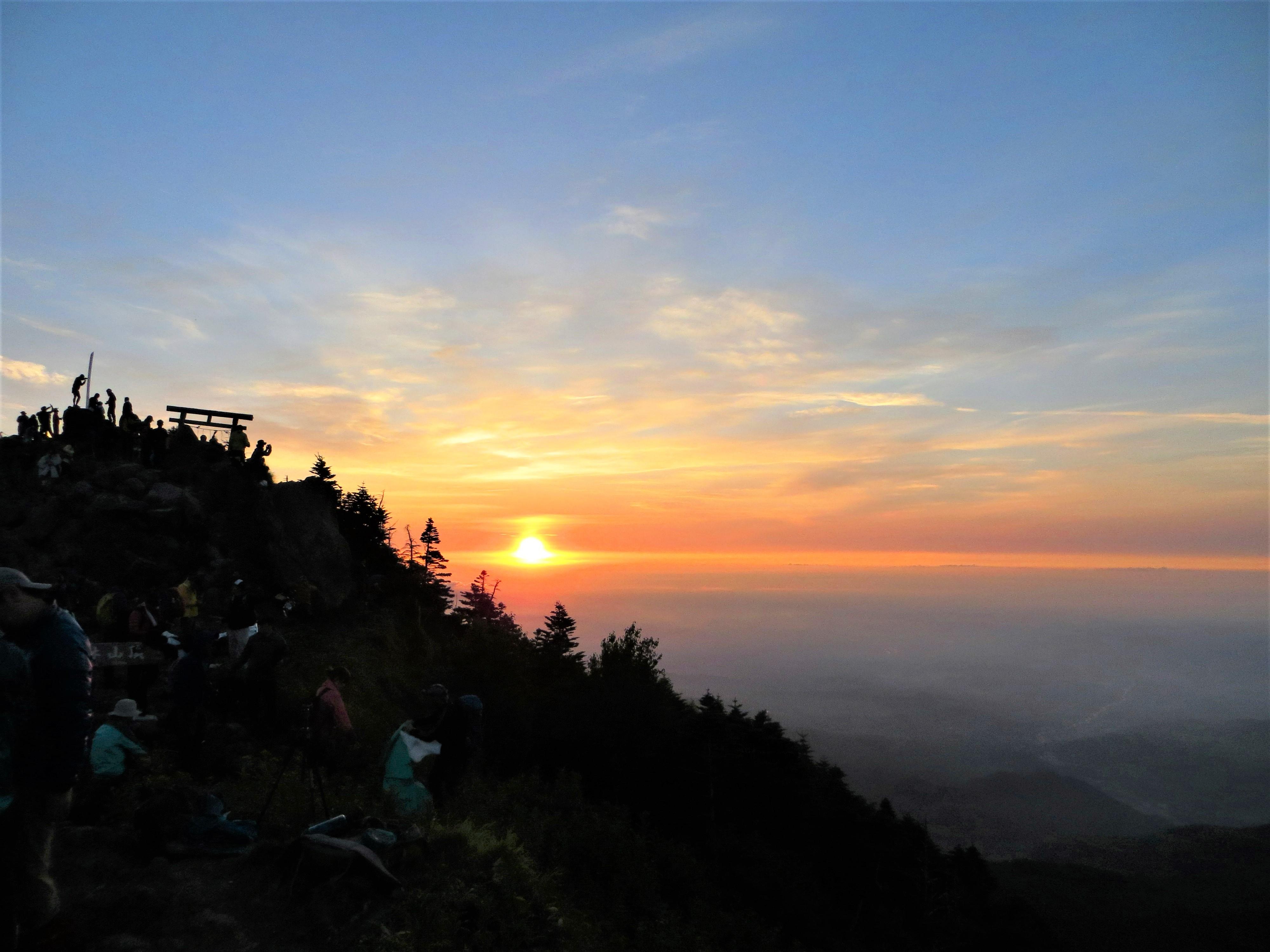 山頂からご来光を見る登山者たち